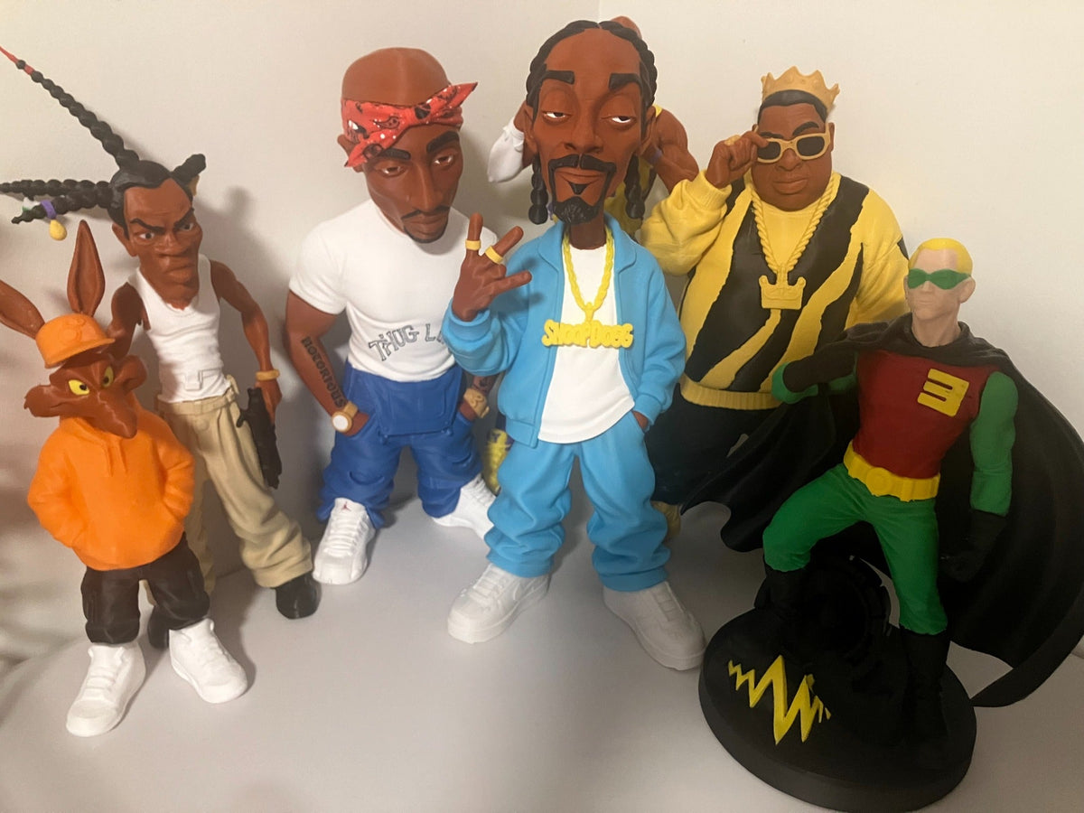 A group of SwagBag.US large 3D-printed caricature figures displayed together, with Snoop Dogg in a blue outfit at the center.